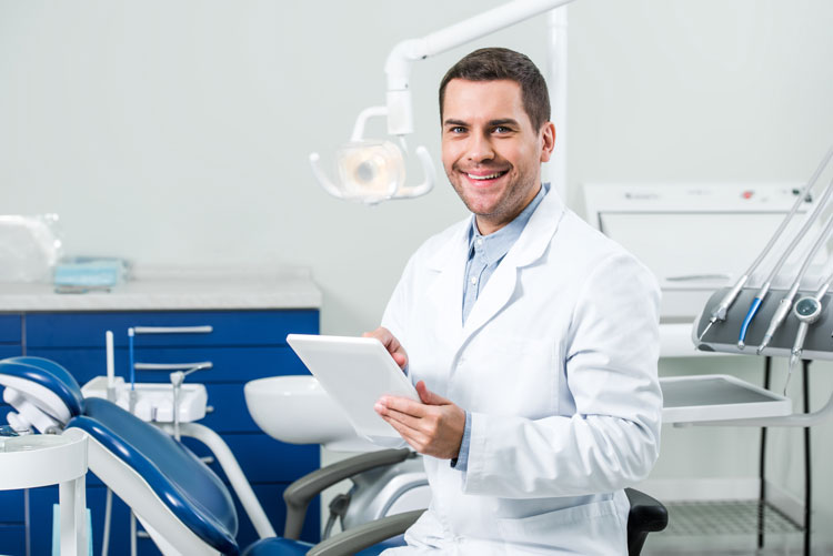 smiling dentist holding tablet