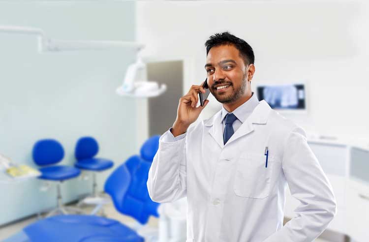 Dentist communicating on phone with consultant.